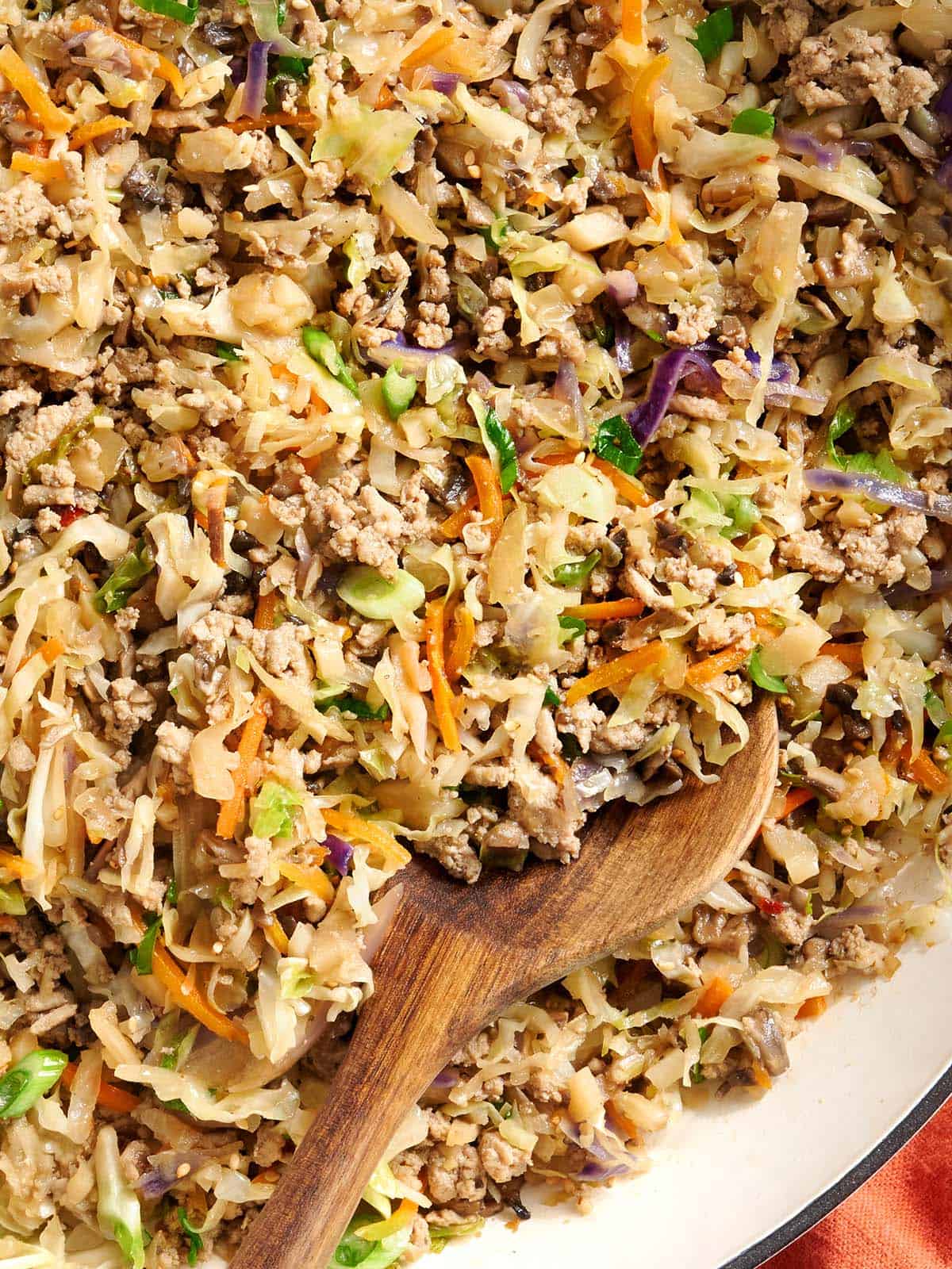close up photo of egg roll in a bowl with a spoon scooping some out