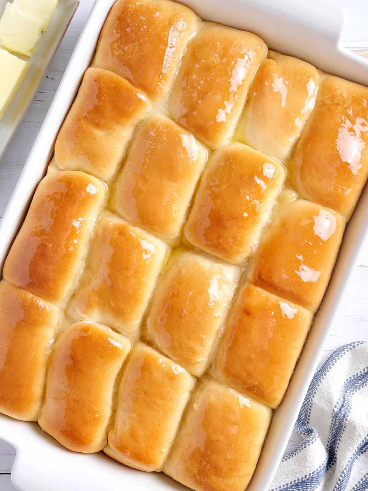 White dish with buttered Parker House rolls.