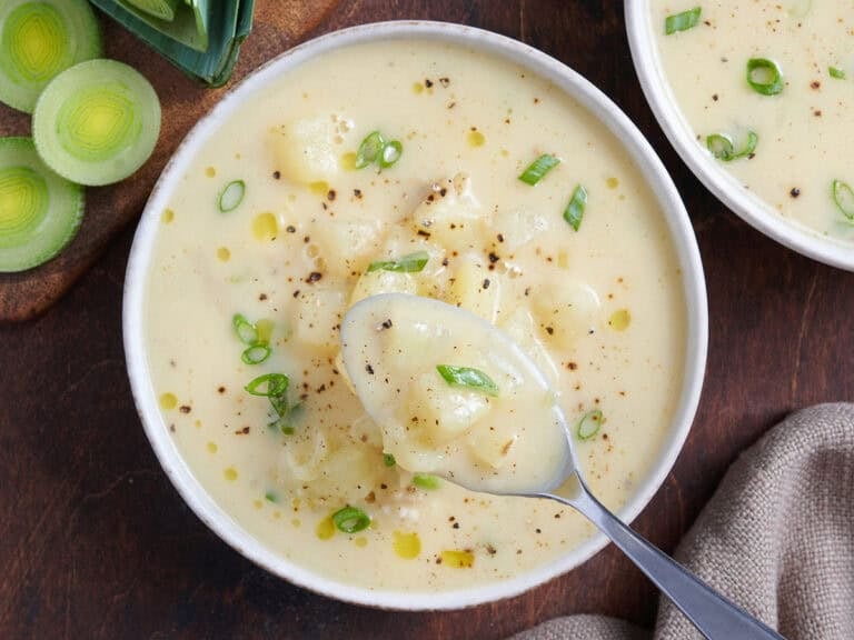 Overhead view of potato leek soup in a bowl with a spoon.