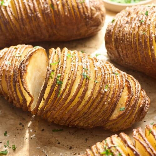 Side view of hasselback potatoes on parchment paper.