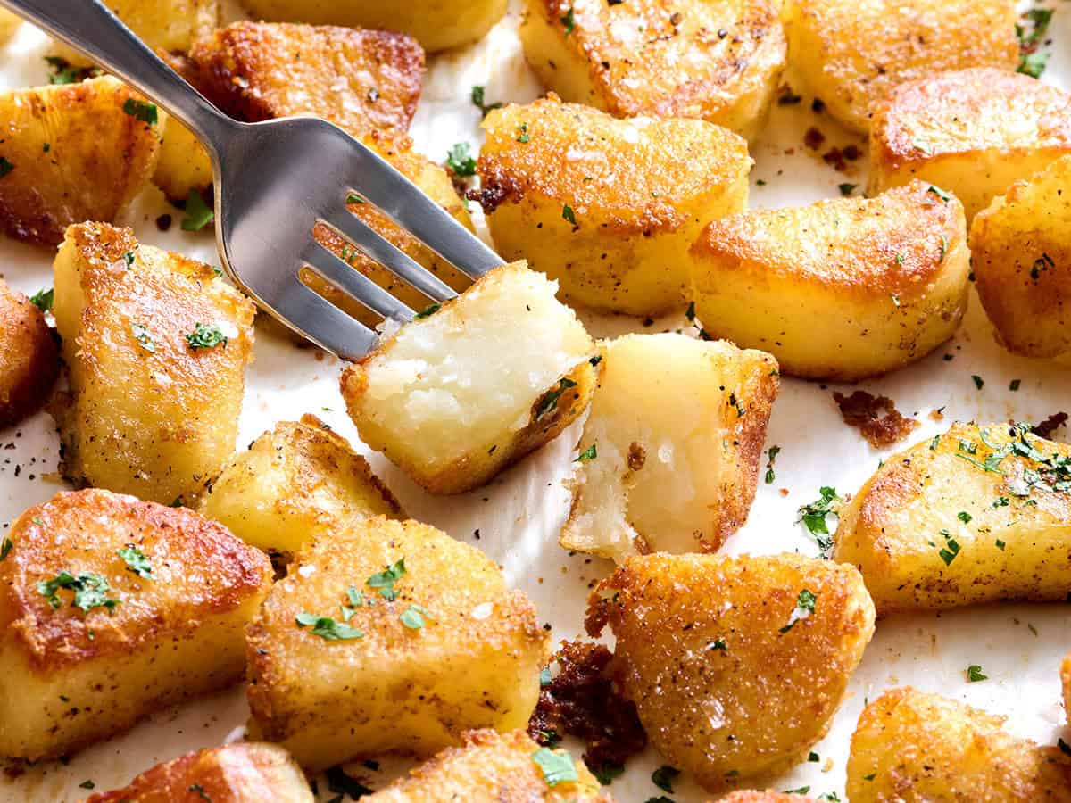 Oven roasted potatoes with one cut open and a fork taking some.