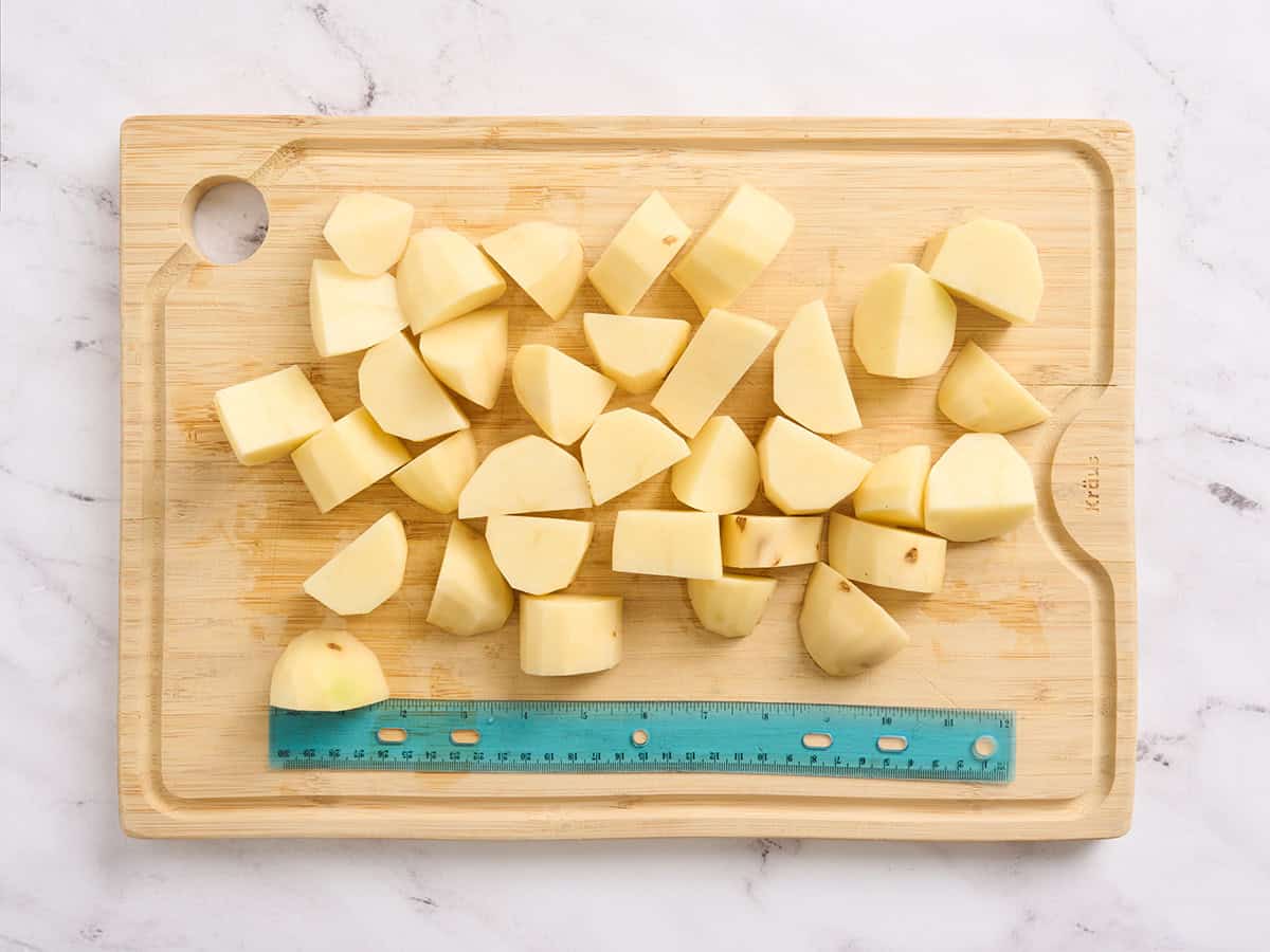 Diced potatoes on a wooden cutting board with a measuring tape.