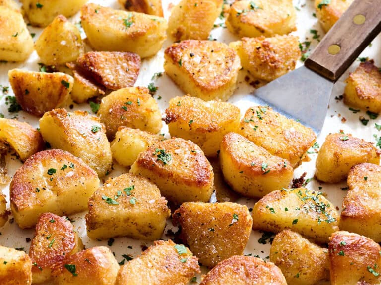 Oven roasted potatoes on a baking sheet with a spatula.