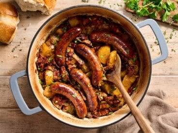 Overhead view of dublin coddle in a dutch oven with a wooden spoon.