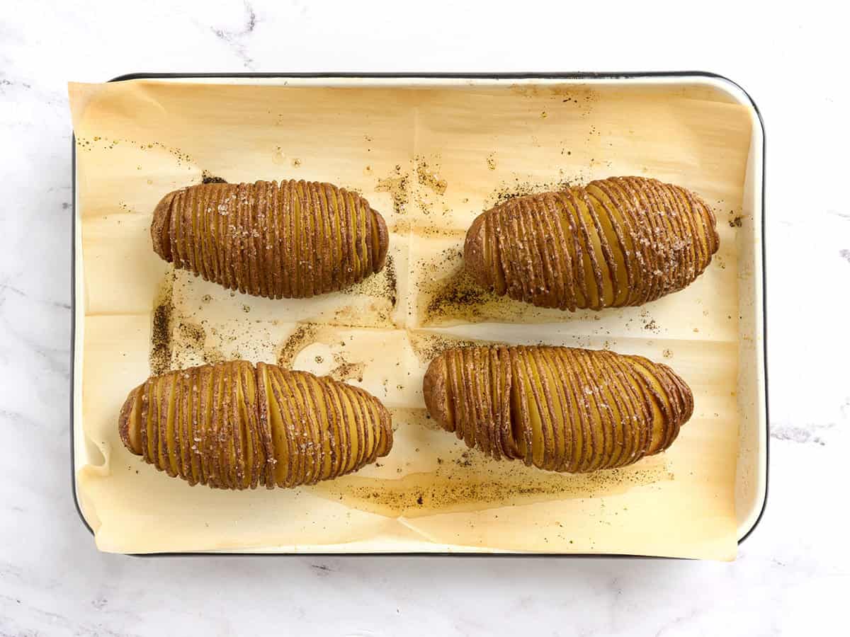 Hasselback potatoes on a parchment lined baking sheet.