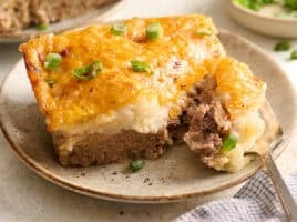 Side view of a slice of meatloaf casserole on a plate with a fork.