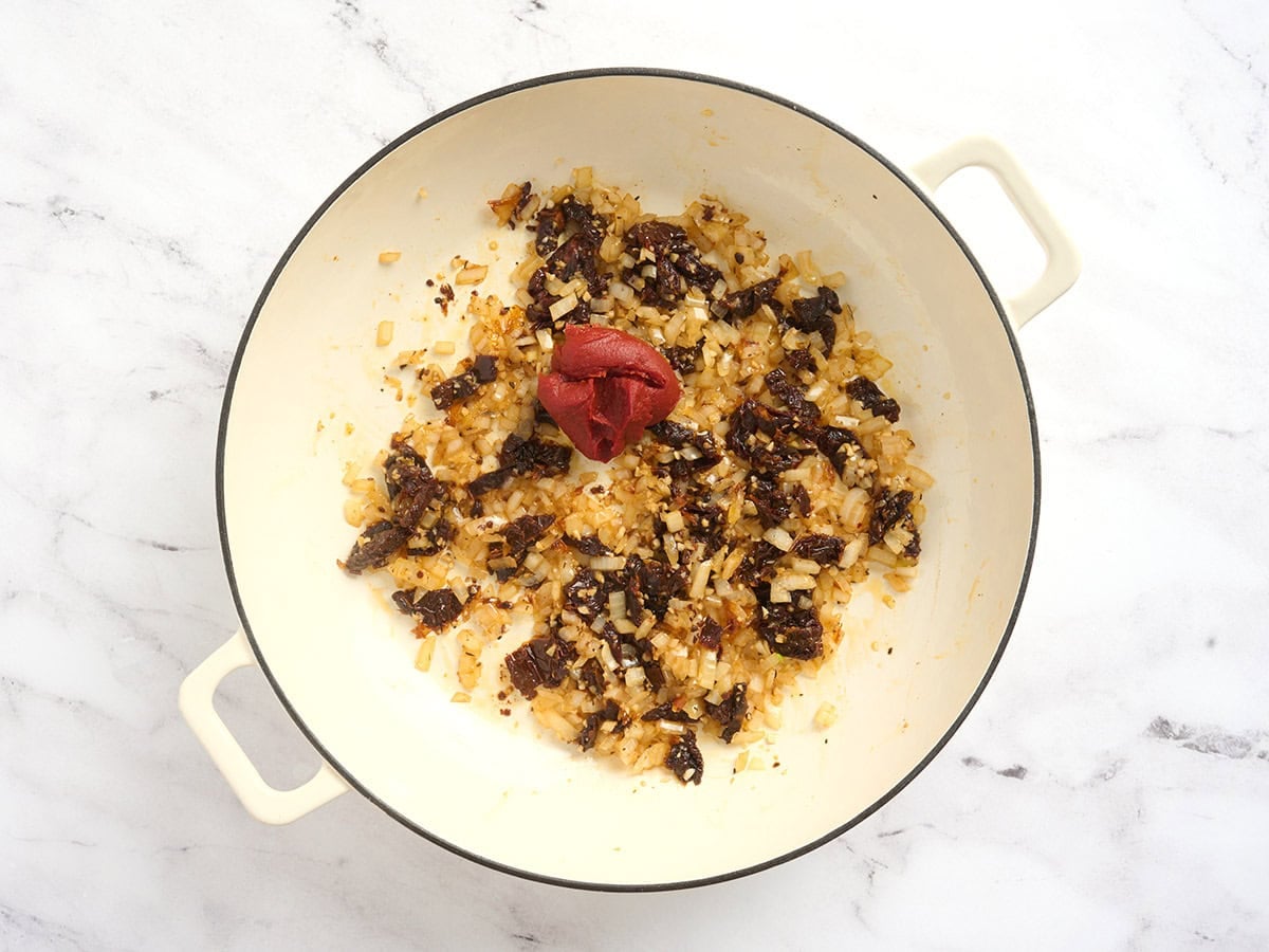 Sauteed onions and garlic in a pot with sun dried tomatoes and tomato paste.