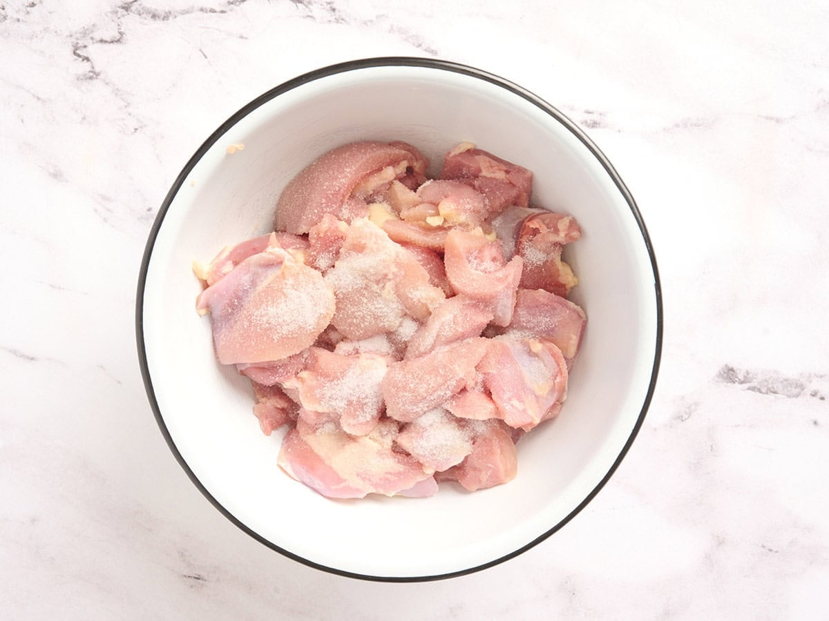 Chicken thighs in a bowl with salt.