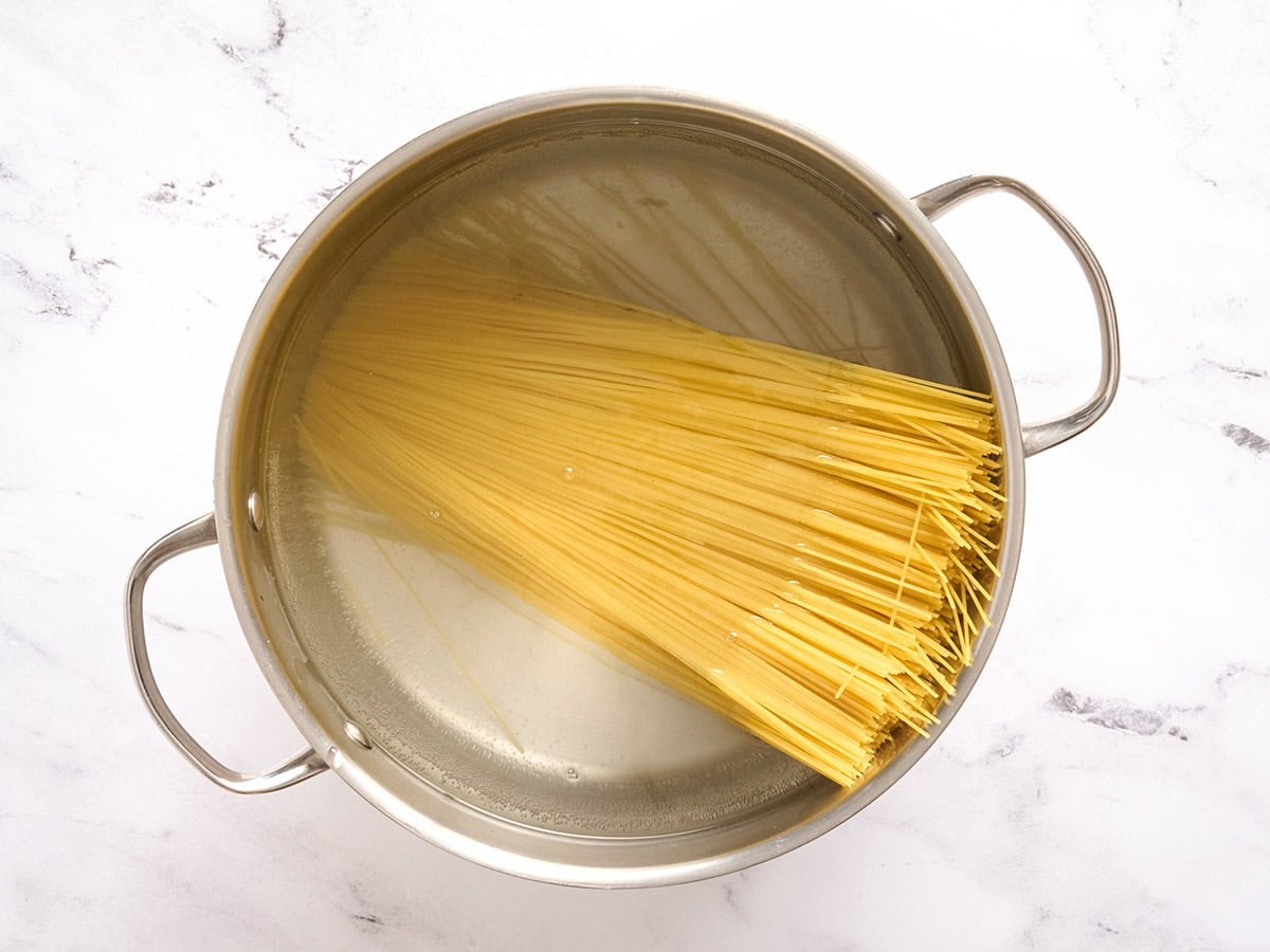 Angel hair pasta added to a pot of water.