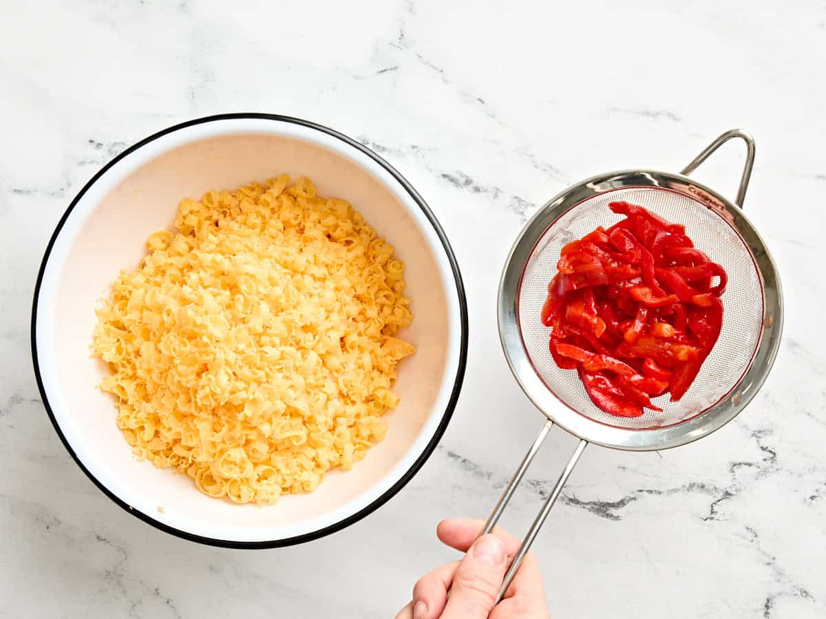 A bowl of shredded cheddar and drained pimentos.