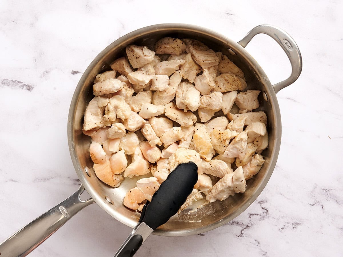 Diced chicken being cooked in a skillet.