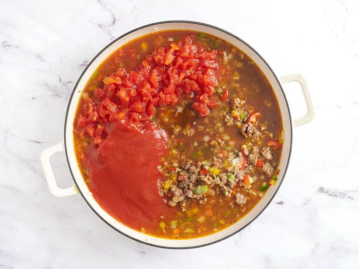 Chopped tomatoes, tomato sauce and veggies in a pot with beef broth.