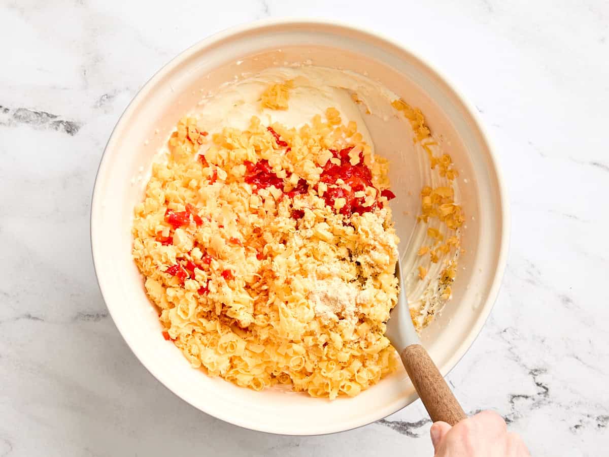 Shredded cheddar and minced pimentos adds to a bowl of combined mayo and cream cheese.