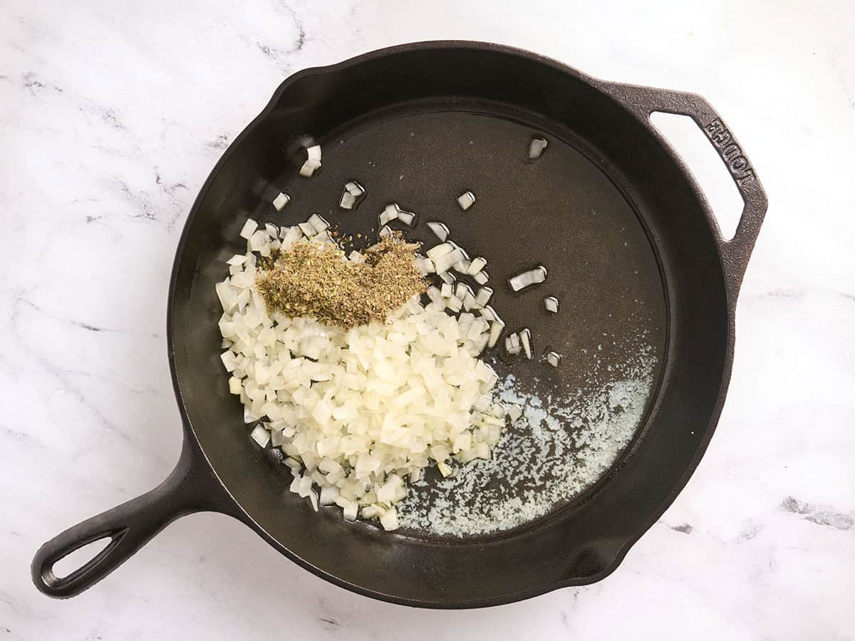 Melted butter, oil, onions, and dried herbs in a skillet.