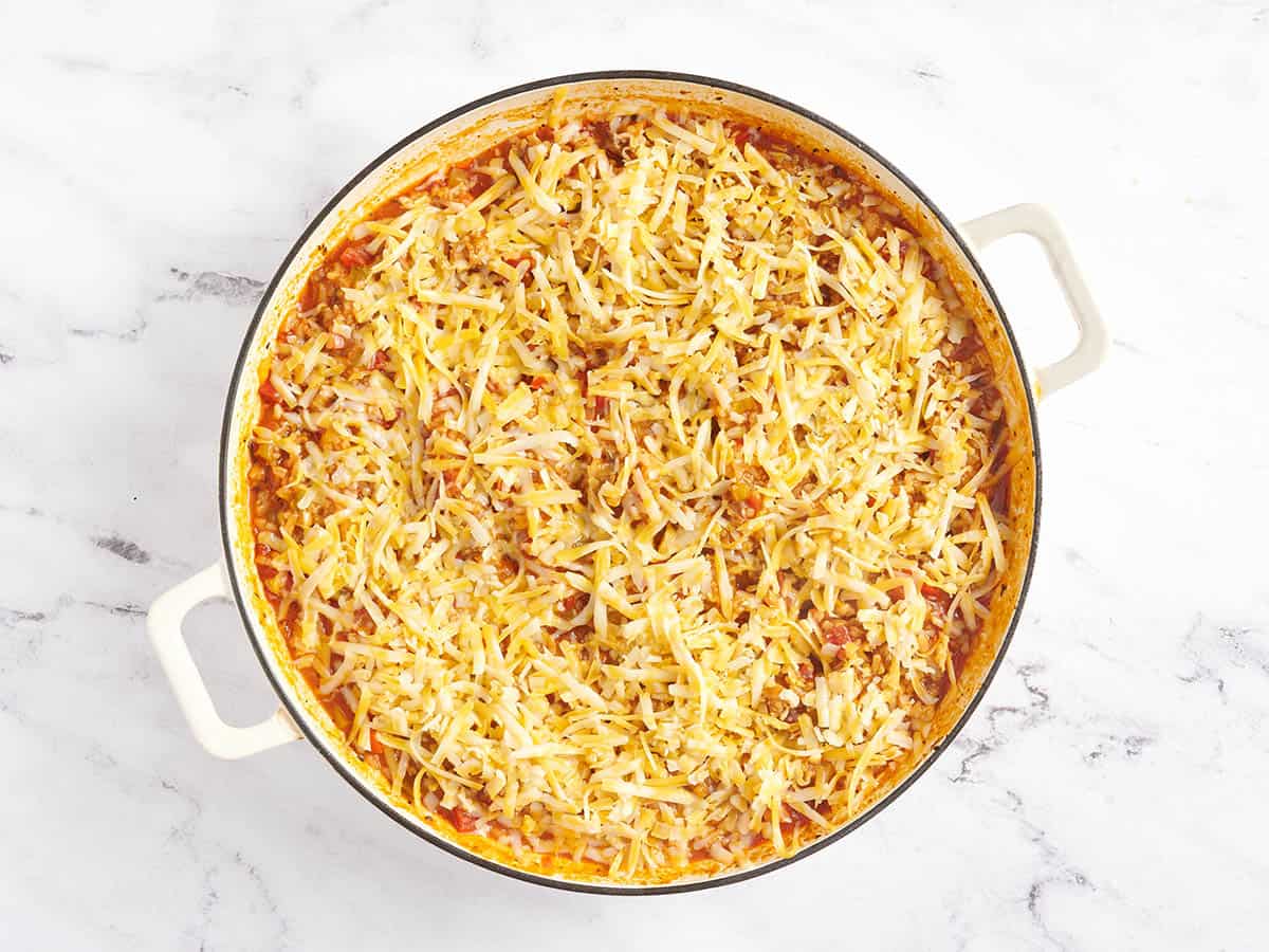 Shredded cheese added to a stuffed pepper skillet.