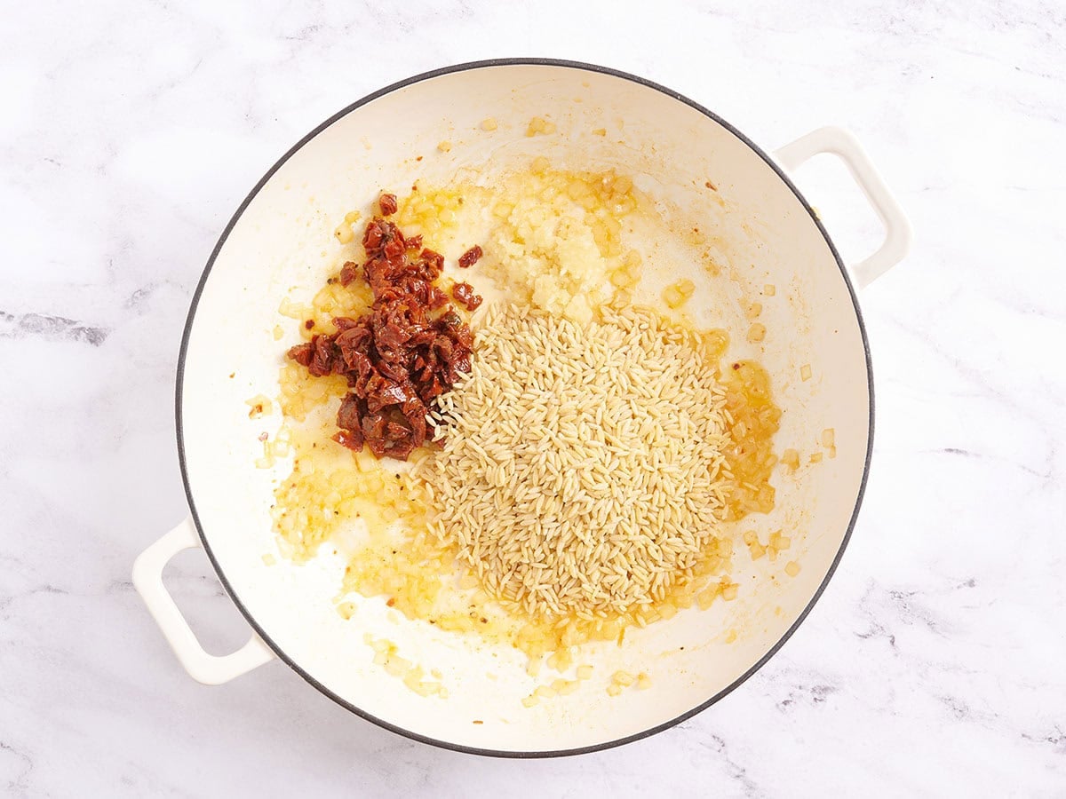 Orzo, diced sundried tomatoes and garlic in a skillet.