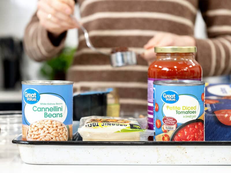 grocery ingredients in front of woman cooking in the background