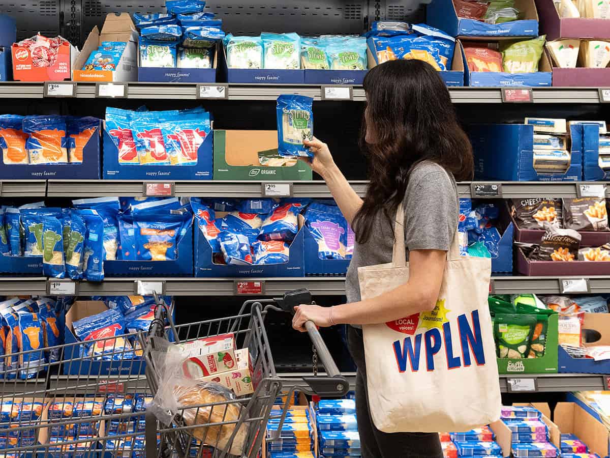 woman shopping at grocery store looking at a pack of cheese