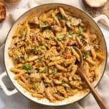 Overhead of marry me chicken pasta in a pot with a wooden spoon.