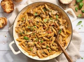Overhead of marry me chicken pasta in a pot with a wooden spoon.