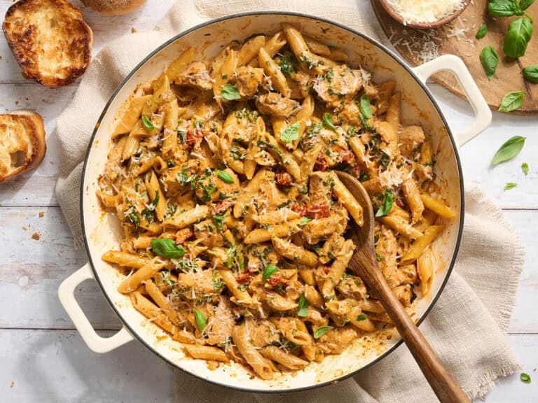 Overhead of marry me chicken pasta in a pot with a wooden spoon.