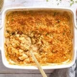Overhead view of a million dollar chicken casserole in a casserole dish with a spoon.