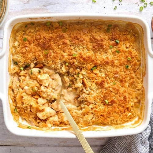Overhead view of a million dollar chicken casserole in a casserole dish with a spoon.