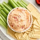 Overhead view of a bowl of pimento cheese with celery and crackers.
