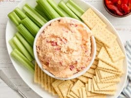 Overhead view of a bowl of pimento cheese with celery and crackers.