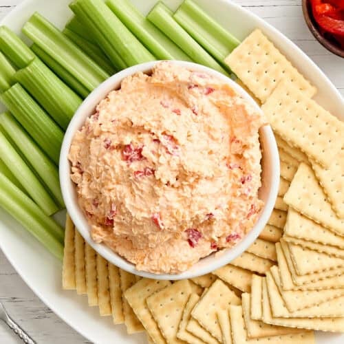 Overhead view of a bowl of pimento cheese with celery and crackers.