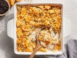 Overhead view of a poppy seed chicken casserole with a wooden spoon.