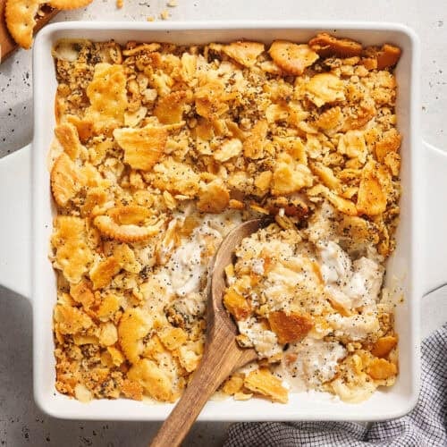Overhead view of a poppy seed chicken casserole with a wooden spoon.