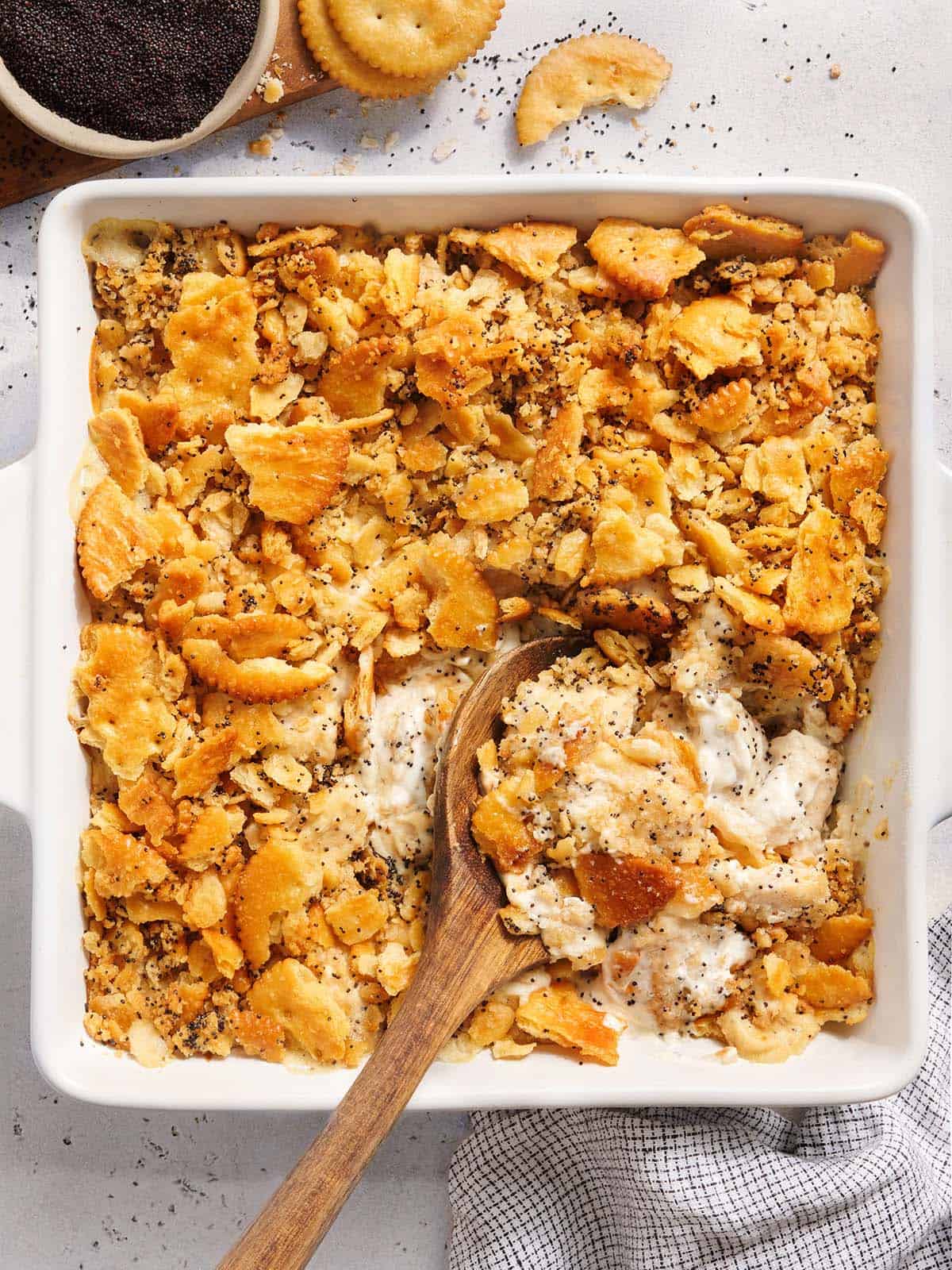 Overhead view of a poppy seed chicken casserole with a wooden spoon.