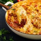 Side view of a spoon taking stuffed pepper skillet from a skillet.