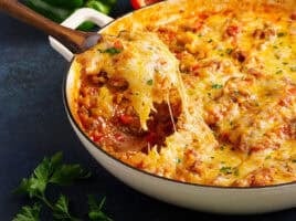 Side view of a spoon taking stuffed pepper skillet from a skillet.