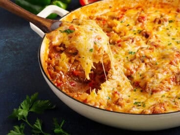 Side view of a spoon taking stuffed pepper skillet from a skillet.