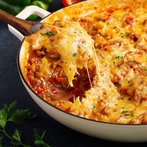 Side view of a spoon taking stuffed pepper skillet from a skillet.