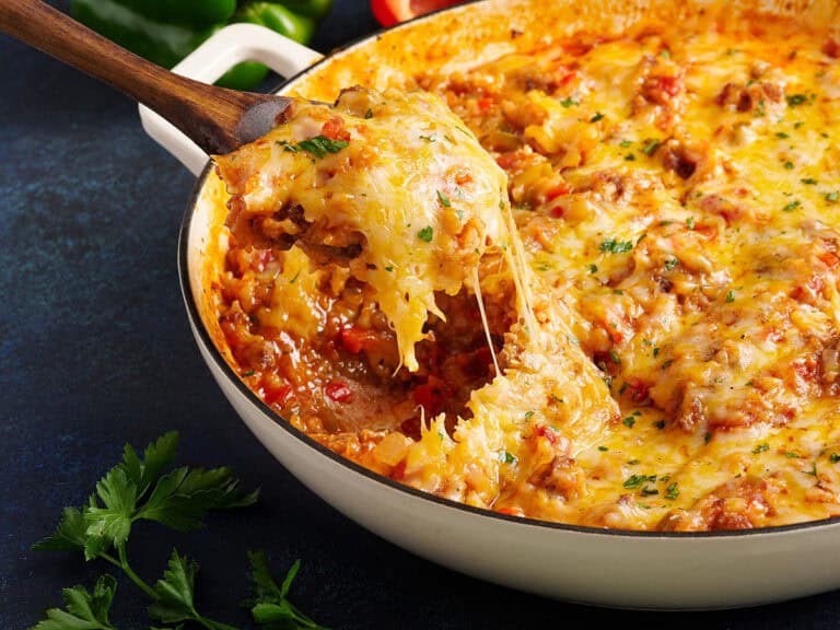 Side view of a spoon taking stuffed pepper skillet from a skillet.