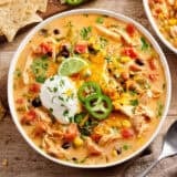 Overhead close up of chicken taco soup in a bowl topped with jalapeno slices and sour cream.