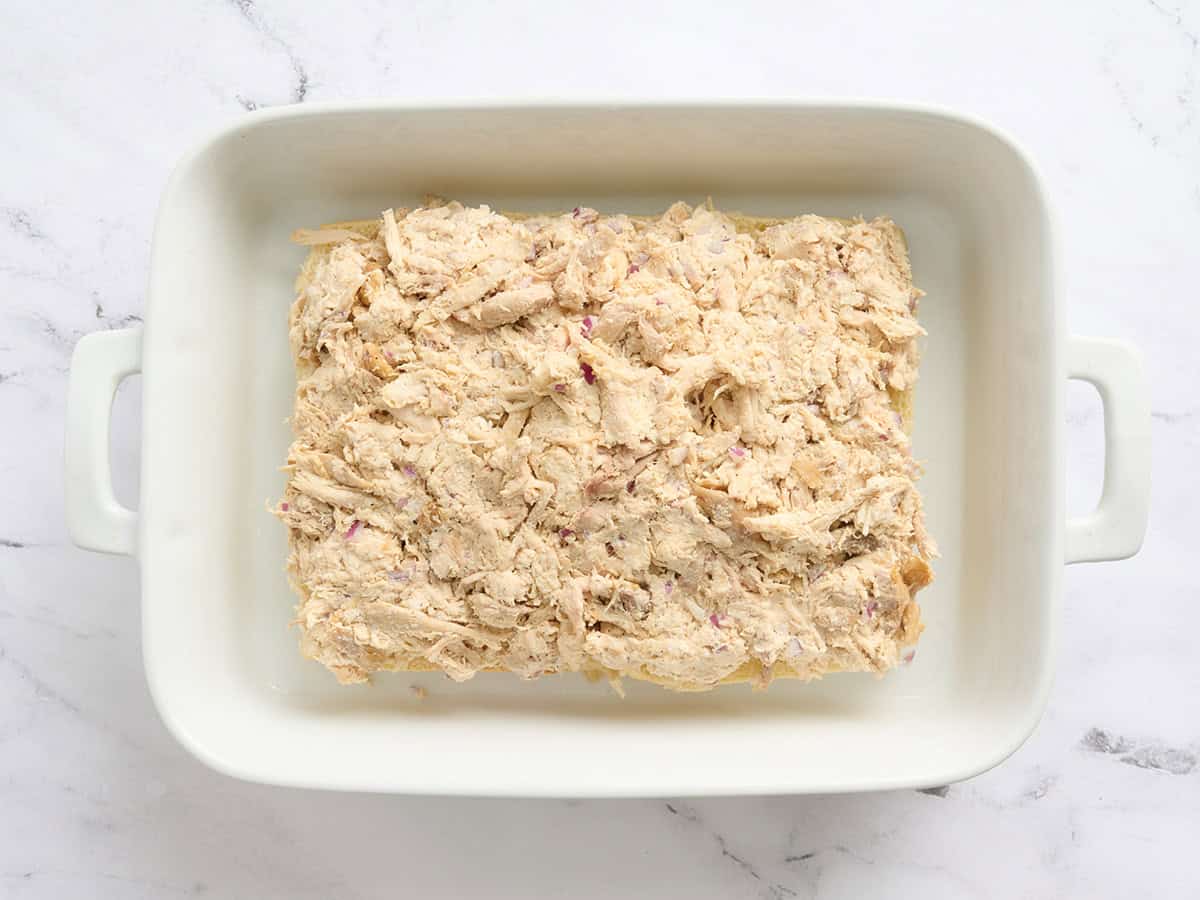 Chicken filling placed on top of hawaiian sliders in a baking dish.