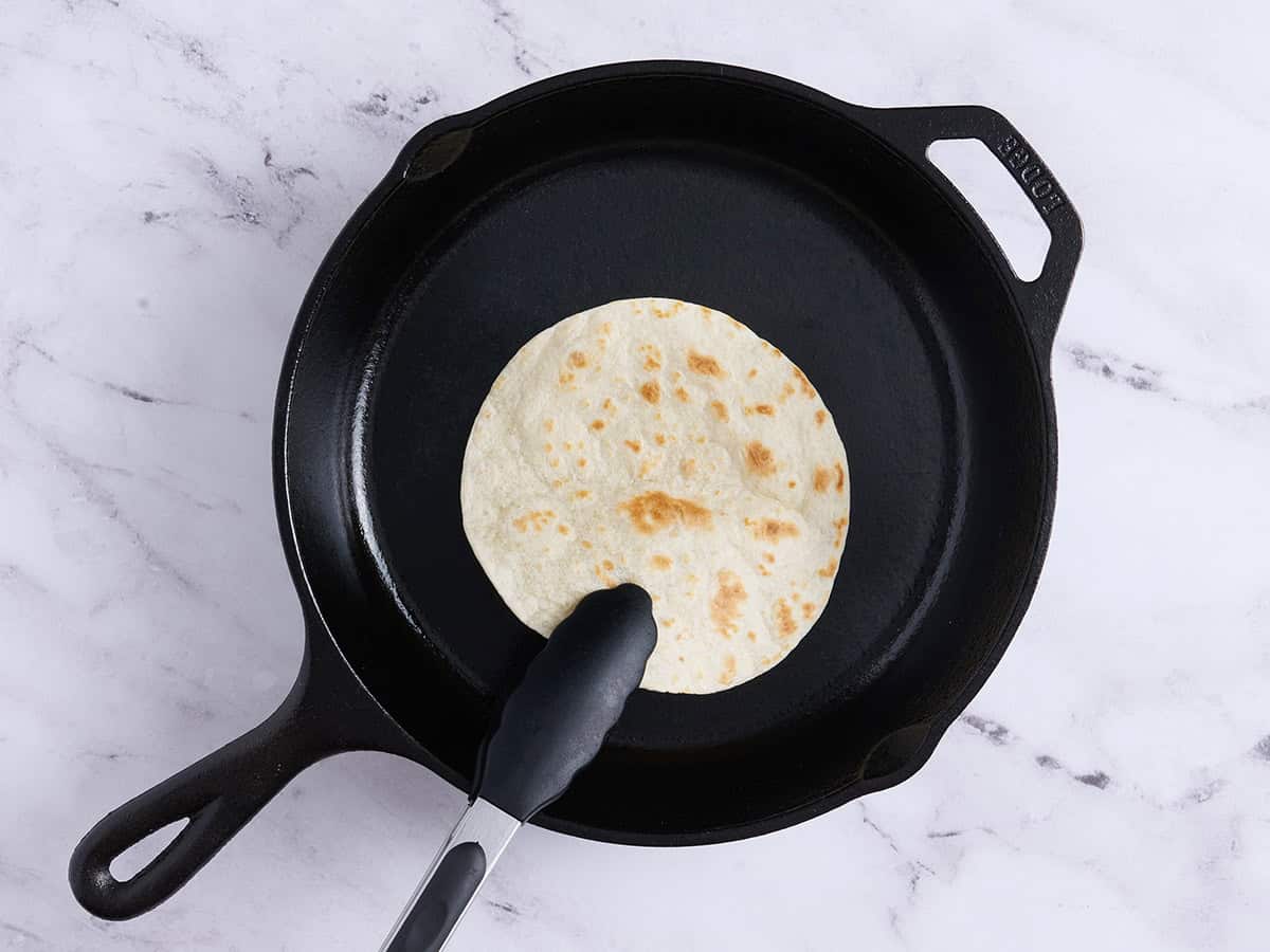 A tortilla toasting in a skillet.