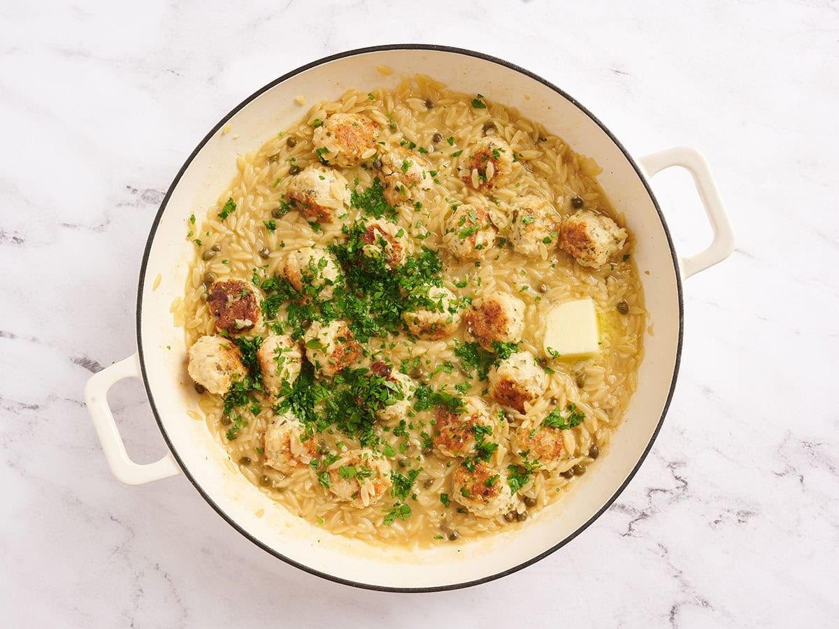 Butter and fresh parsley added to a chicken piccata meatball and orzo skillet.