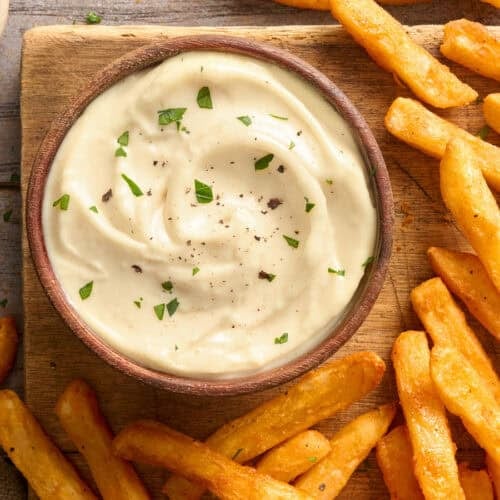 Overhead view of a bowl of homemade garlic aioli with fries.