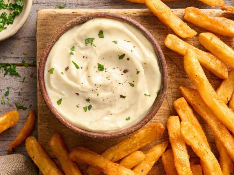 Overhead view of a bowl of homemade garlic aioli with fries.