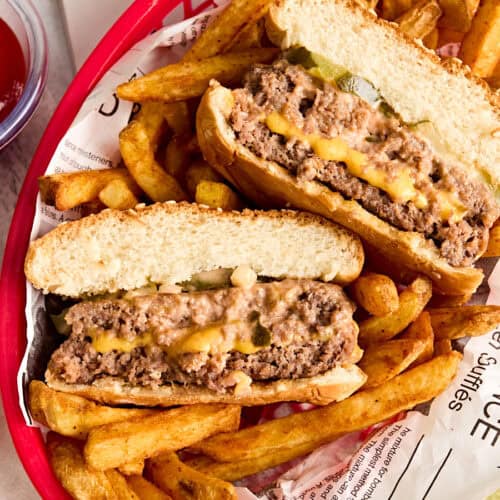 Overhead view of a cheese stuffed juicy lucy burger in a basket with fries.
