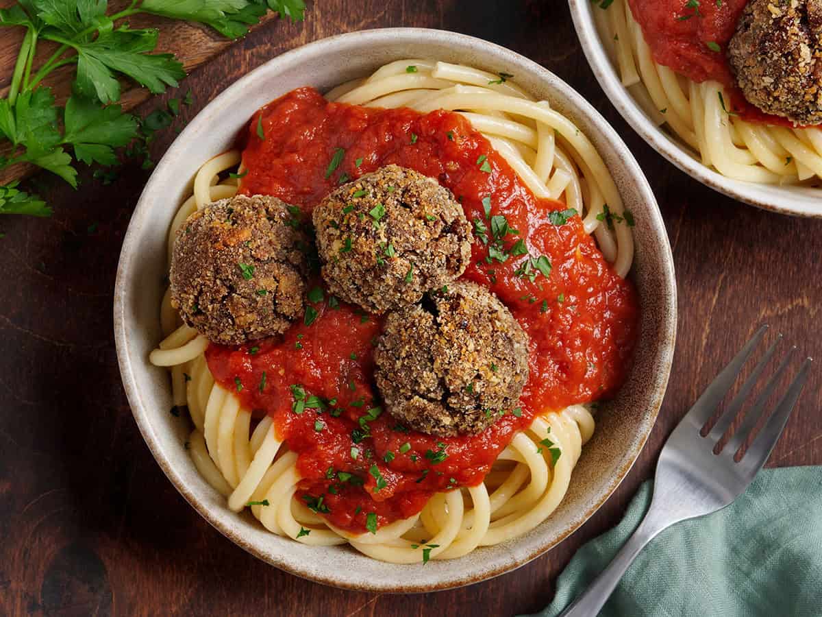 Overhead view of veggie meatballs in a bowl with spaghetti and tomato sauce.