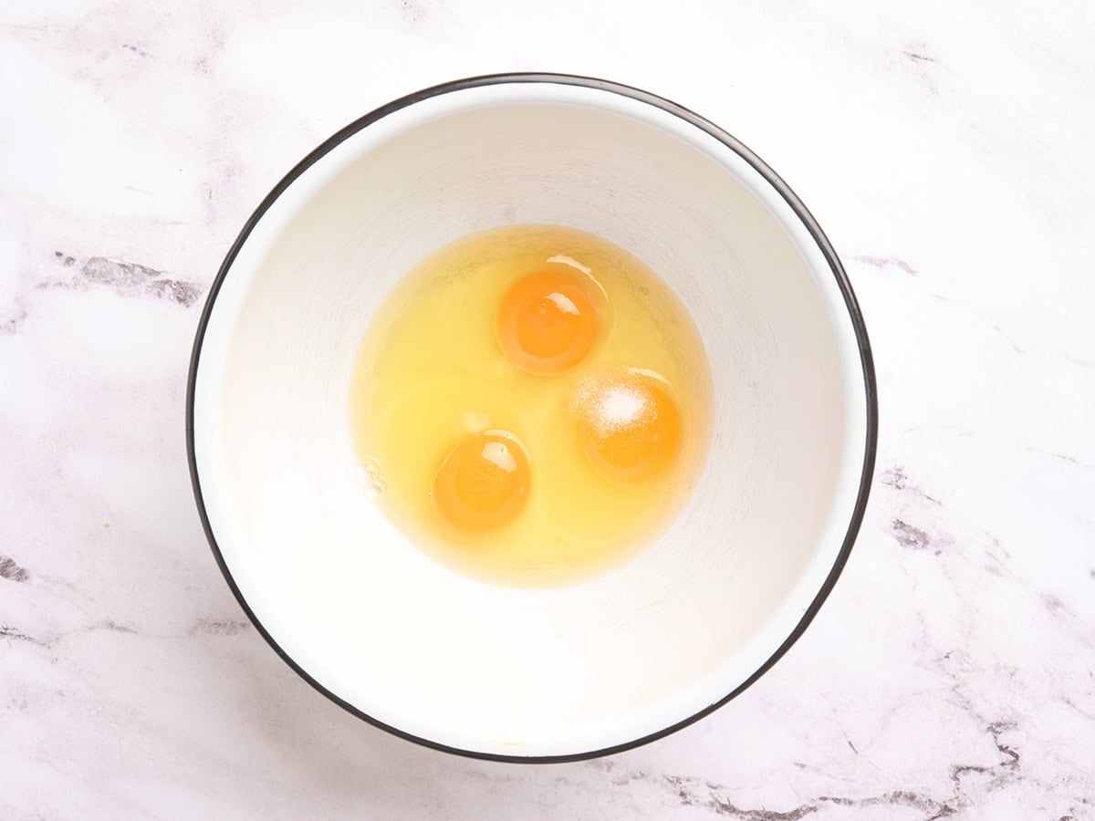Three cracked eggs in a mixing bowl.