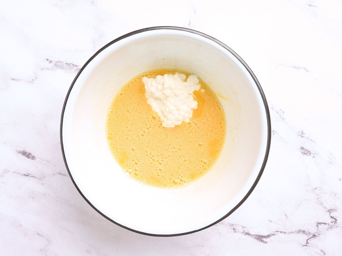 Beaten eggs in a bowl with cottage cheese added.