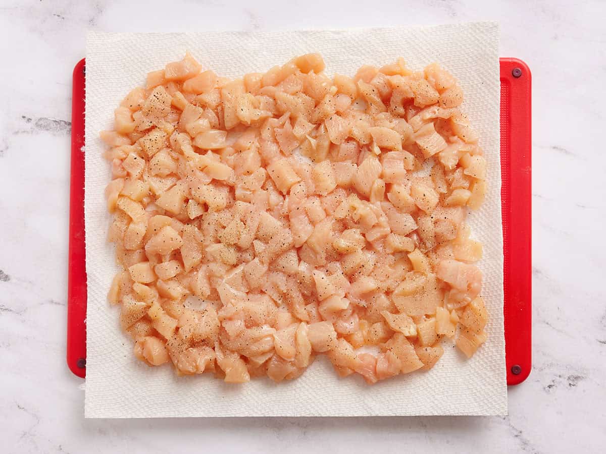 Diced chicken on a cutting board with parchment paper.