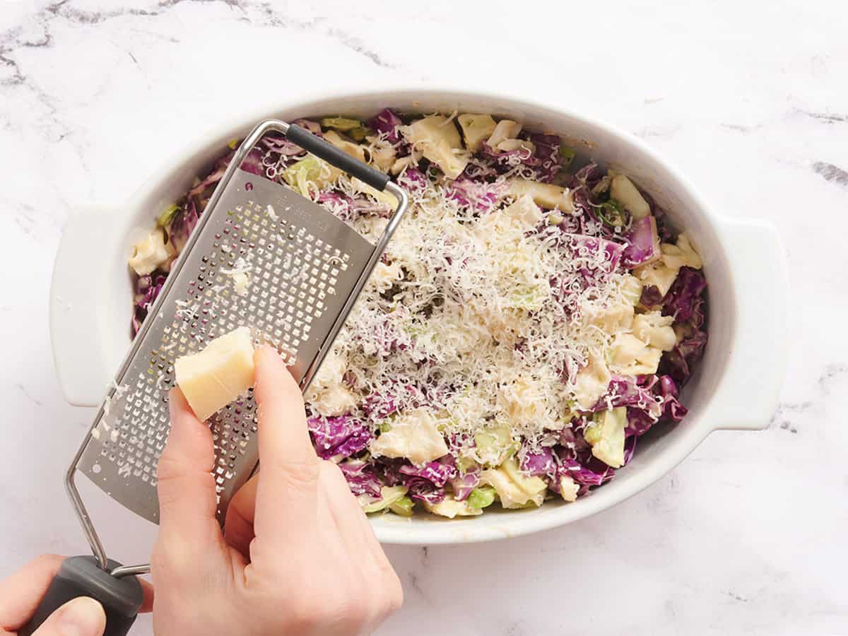 Parmesan cheese being shredded into Caesar slaw.